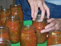 jars of salsa with someone attaching a lid