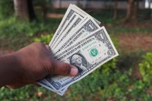 a hand holding several dollar bills